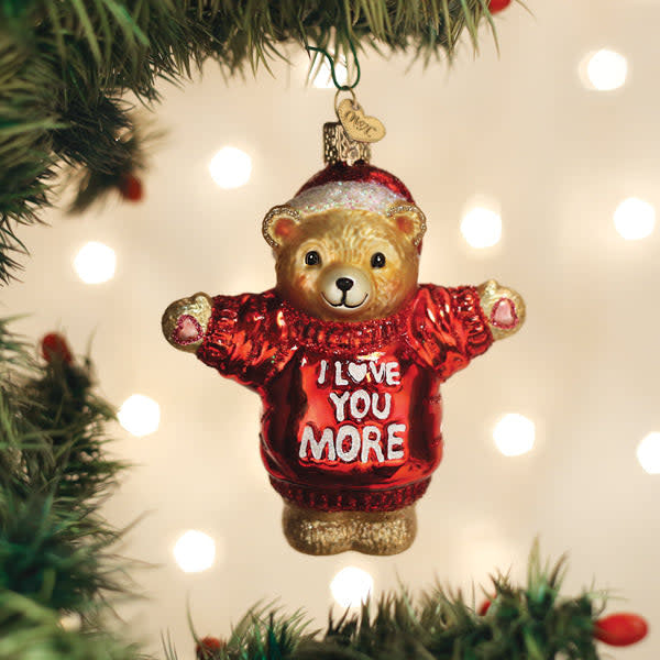 Red glass ornament shaped like a teddy bear with 'I Love You More' text on its chest.
