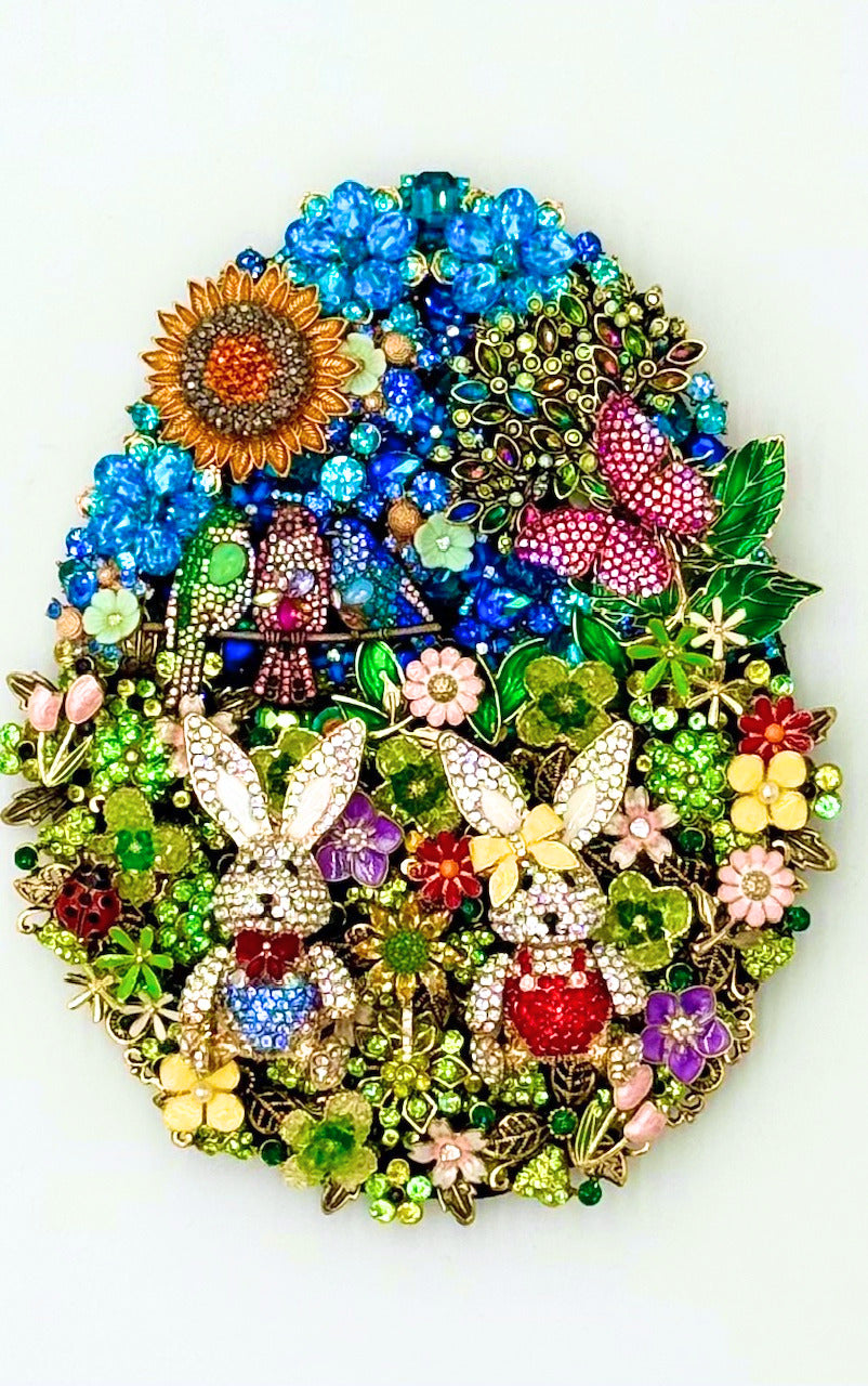 Jeweled egg-shaped art featuring two bunnies, birds, a sunflower, and flowers in vibrant colors.