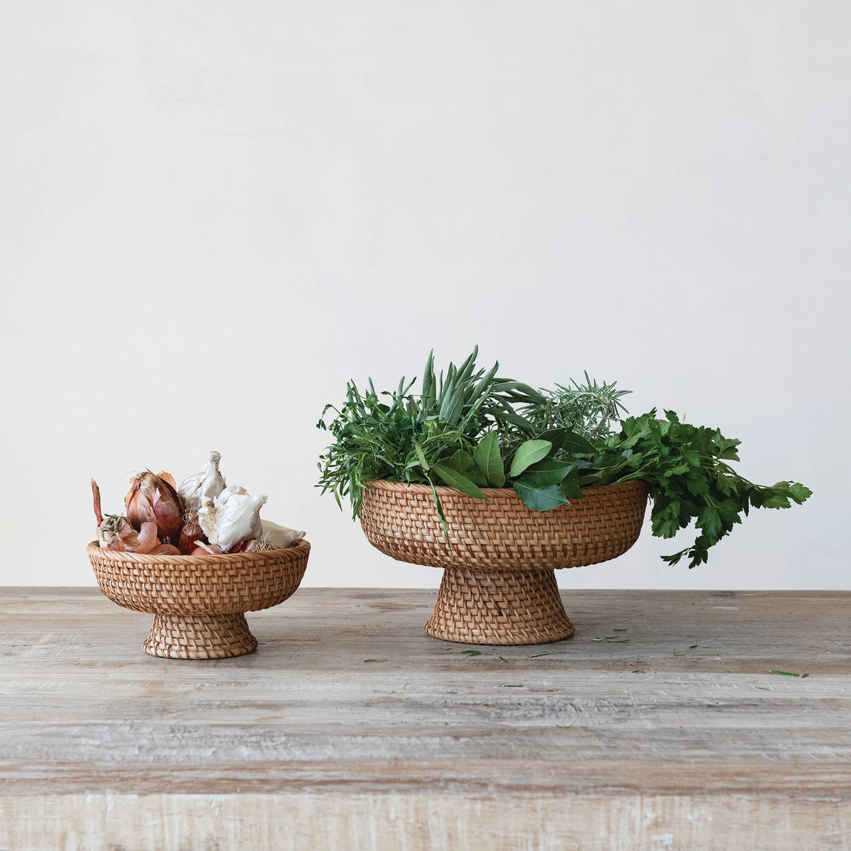 Two round natural rattan footed bowls with decorative woven texture.