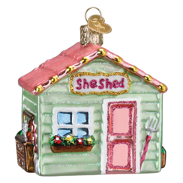 Glass She Shed Christmas ornament with a pink roof, green walls, and a glittery sign.