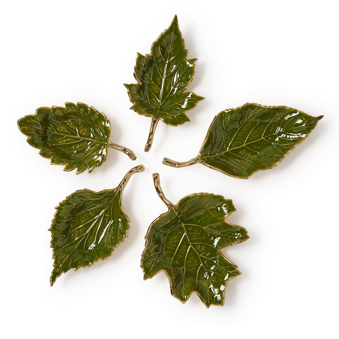 Set of five green enameled leaf-shaped trays with gold metallic edges and stems on a white surface.