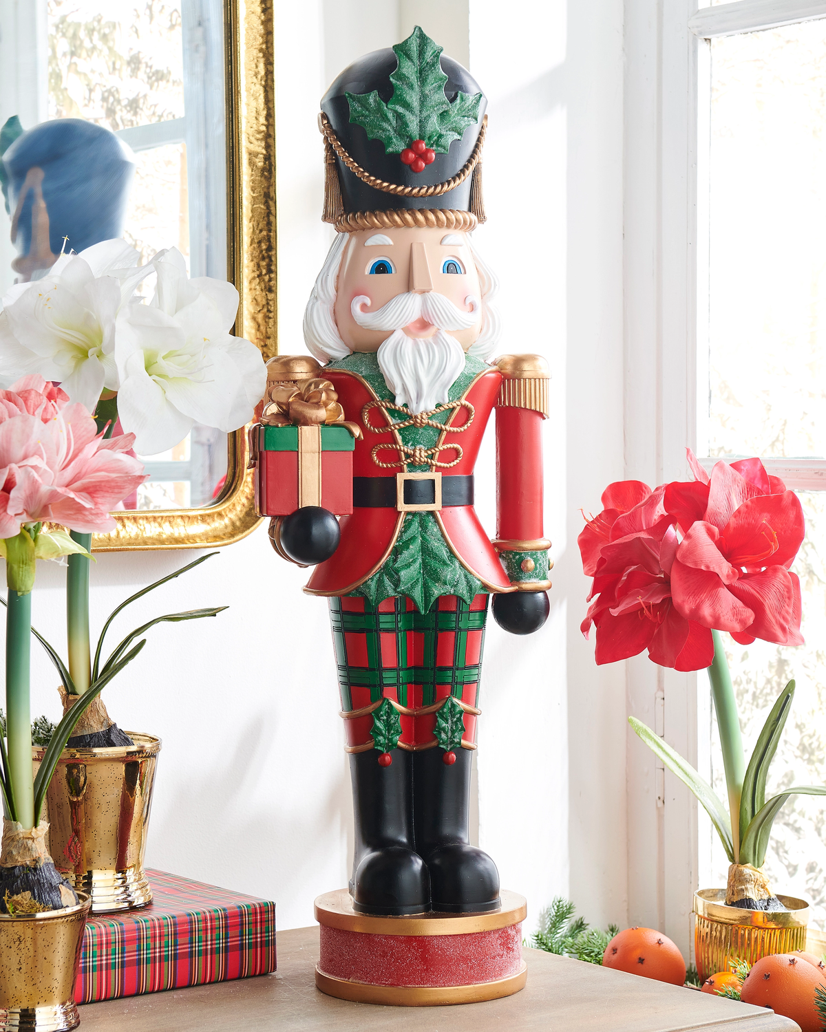 A 32-inch nutcracker figure wearing a red jacket and plaid pants, holding a gift box.