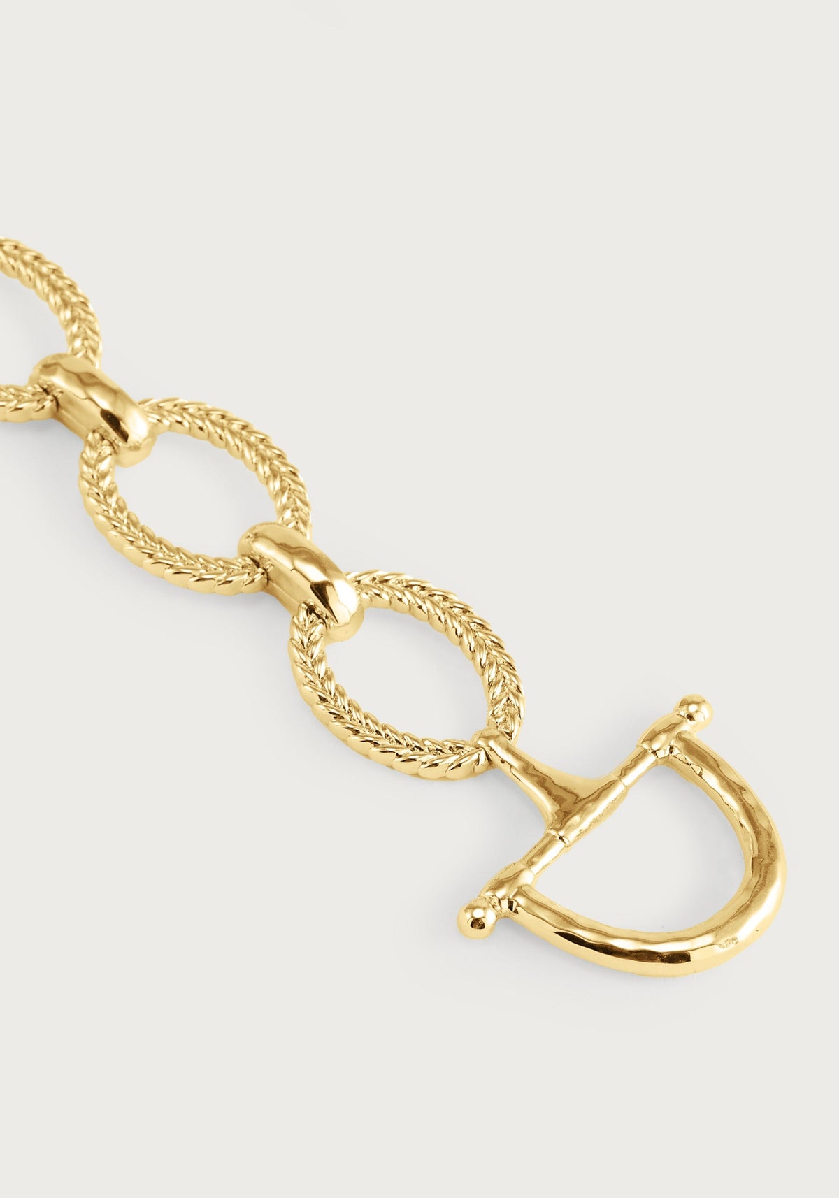 Close-up of a gold-plated Cheval Chain Bracelet featuring braided links and a horse bit clasp.