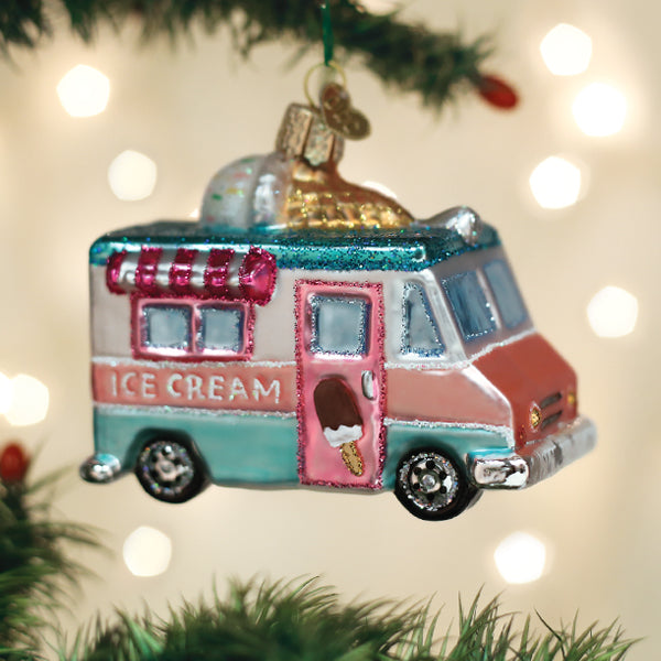 Glass ice cream truck Christmas ornament with pink and teal glitter accents hanging on a tree.
