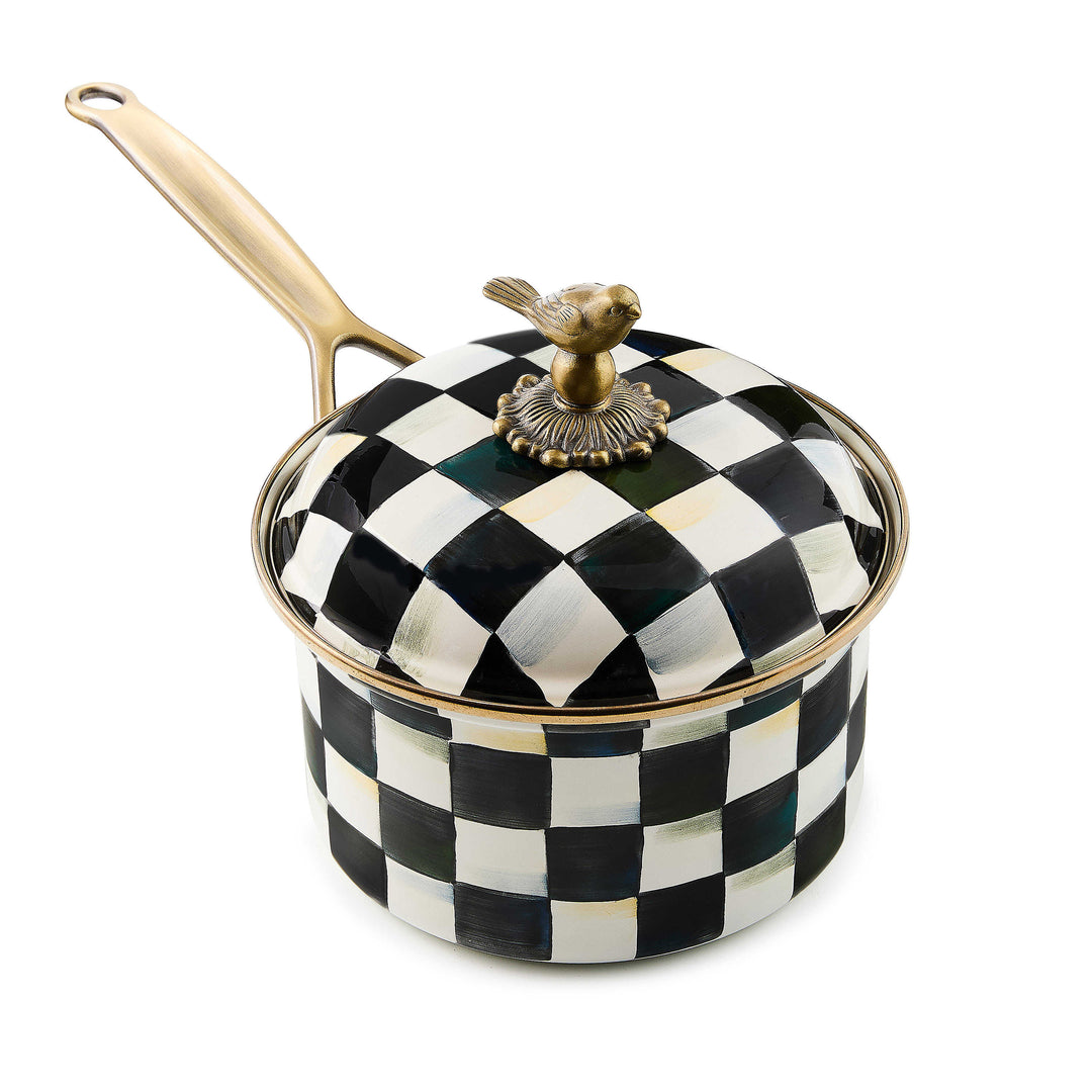 Black and white checkered enamel saucepan with a brass handle and a bird-shaped lid knob.