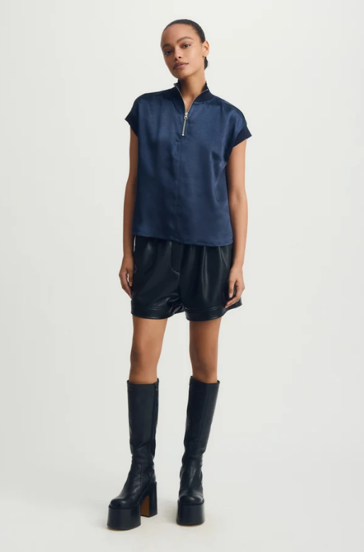 Woman wearing a navy blue Hera Mixed Media Satin Top with a half-zip collar and short sleeves.