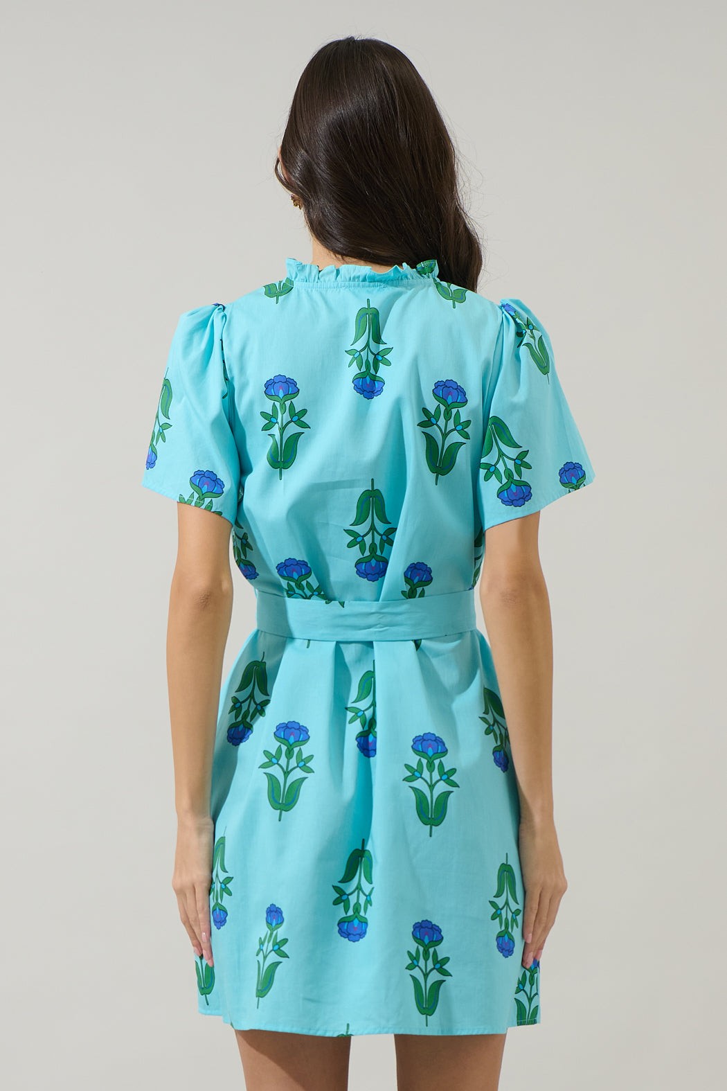 Back view of a woman wearing the light blue Amena Floral Ema Shift Mini Dress with a belted waist.