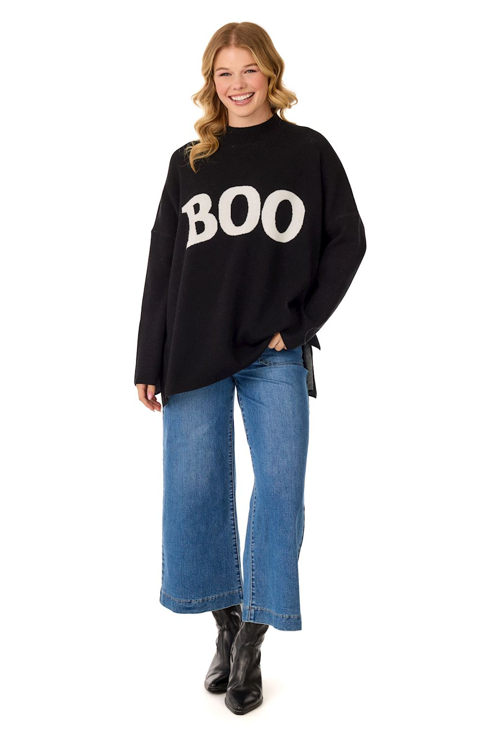 Woman wearing a black jacquard mock neck sweater with white 'BOO' text and blue wide-leg jeans.