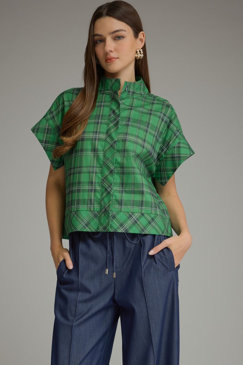 Woman wearing a green Chloe Plaid Short Sleeve Top with a high collar and dark blue trousers.