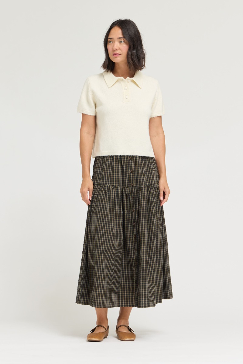 Woman wearing the Marian ivory short sleeve knit top with a collar and buttoned half-placket.