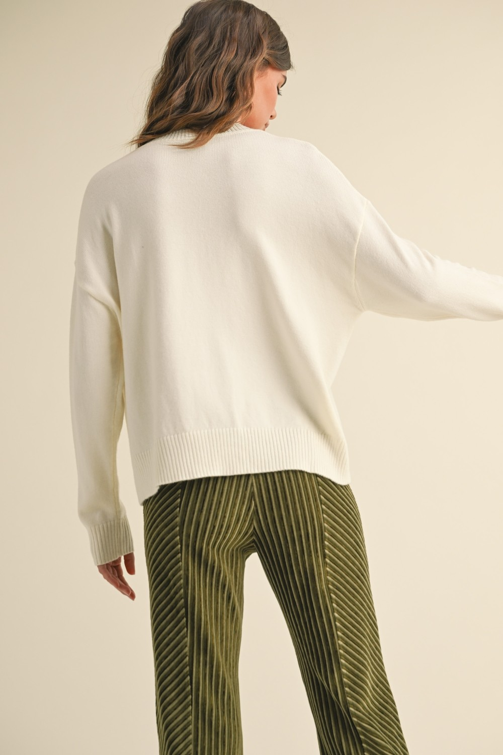 Back view of a woman wearing the Ailsa white striped sweater with olive green corduroy pants.
