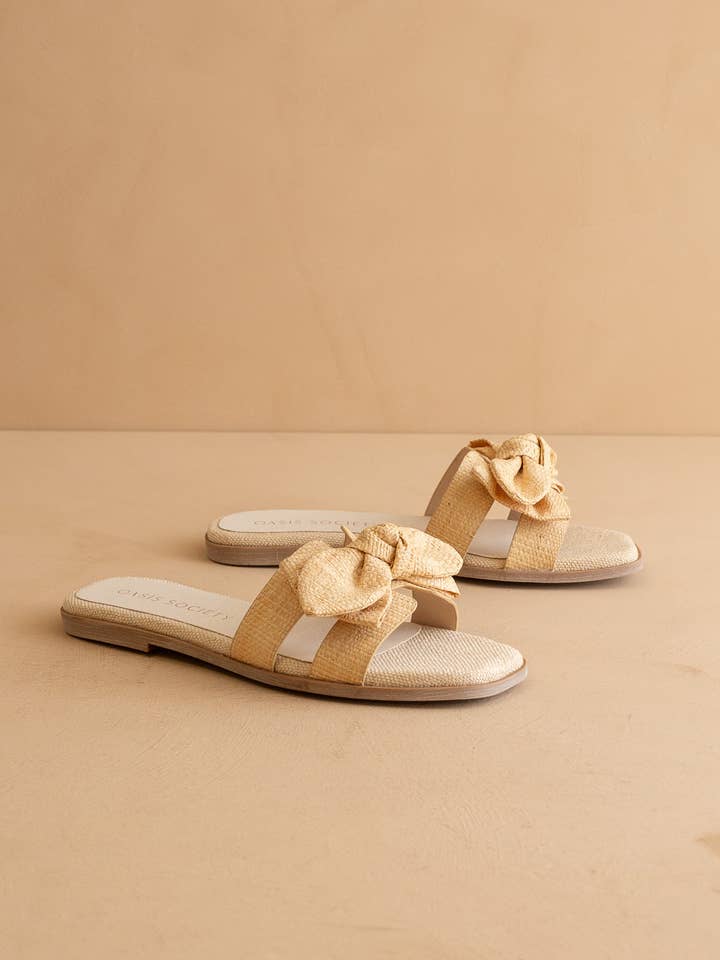 The Ginny Textured Bow Slide in a natural straw-like material with a cushioned sole.