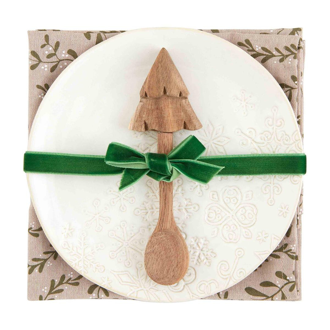 White Christmas appetizer set with snowflake plate, tree-topped wooden spoon, and patterned towel.