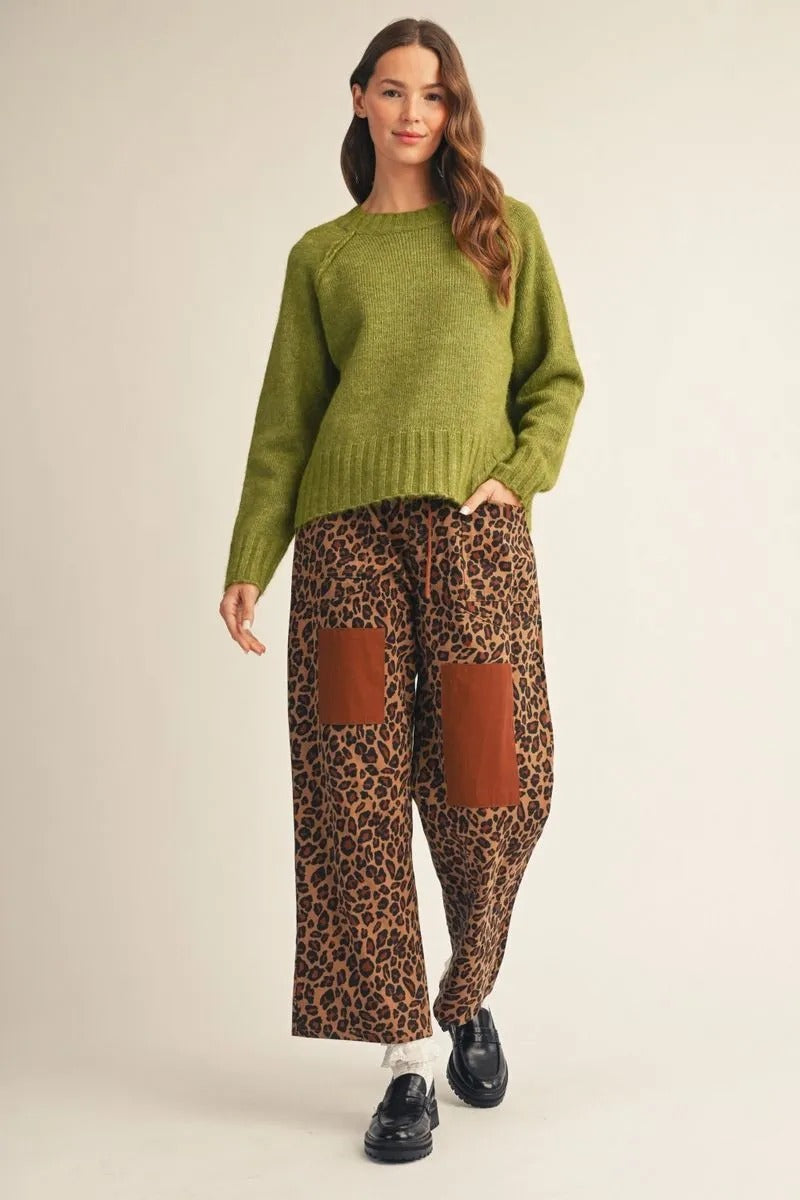 Woman wearing a green Avery long raglan sleeve round neck comfy sweater top with leopard pants.