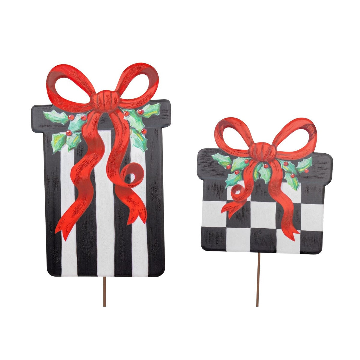 Two decorative gift box yard stakes, one with black and white stripes, the other with a checkerboard pattern, both adorned with red bows and holly.