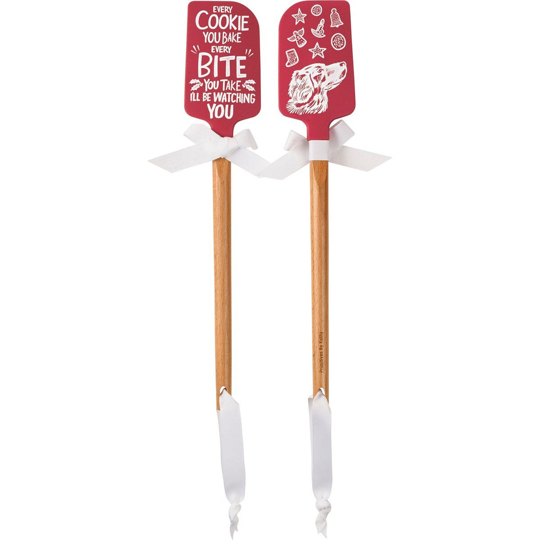Black silicone spatula with wooden handle featuring red Christmas-themed designs.