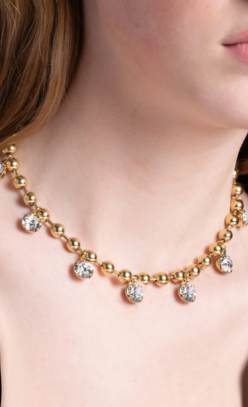 Emery Necklace featuring gold bead links and dangling crystal charms worn on a model's neck.