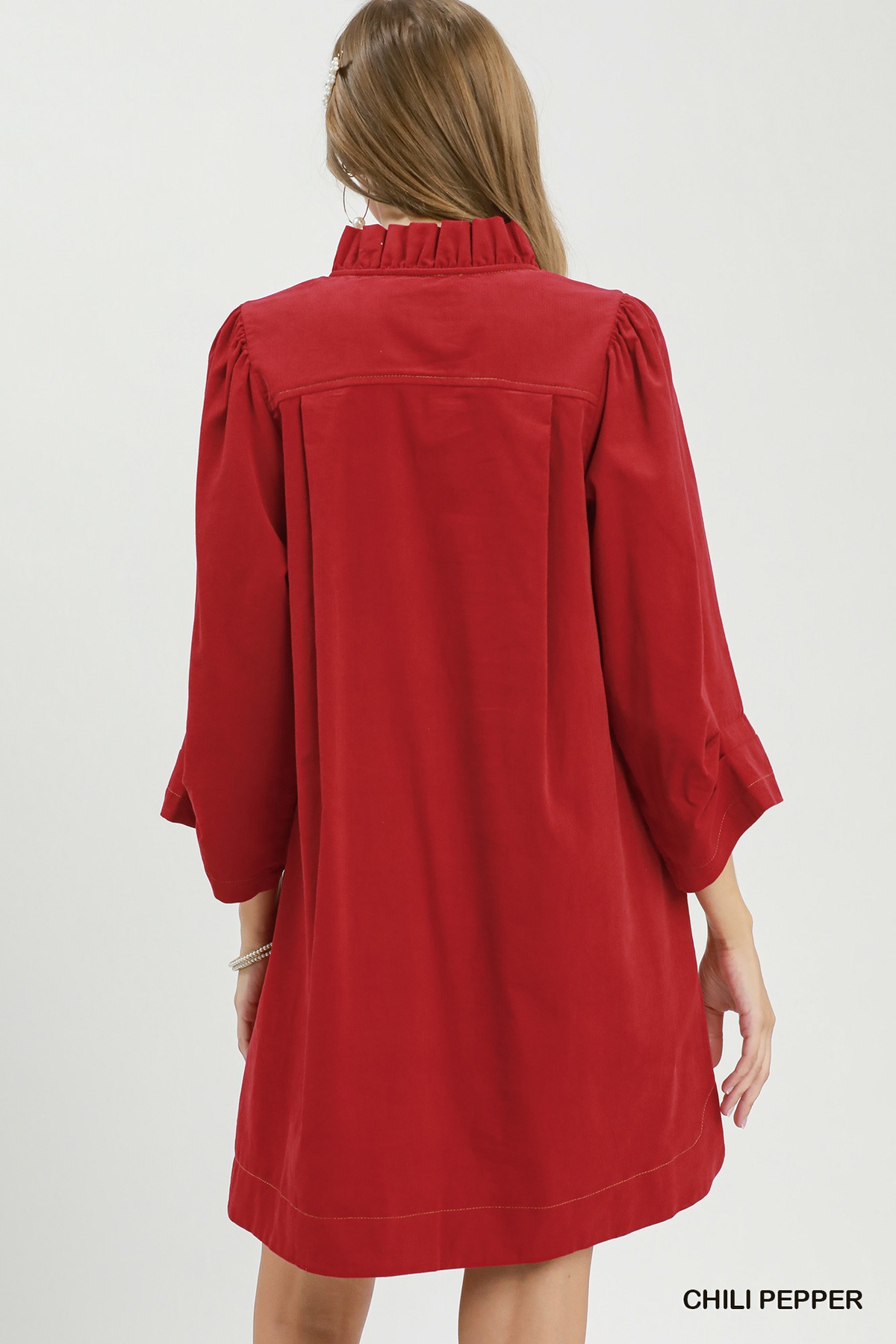 Back view of a woman wearing a red corduroy shift dress with a ruffled collar and puff sleeves.