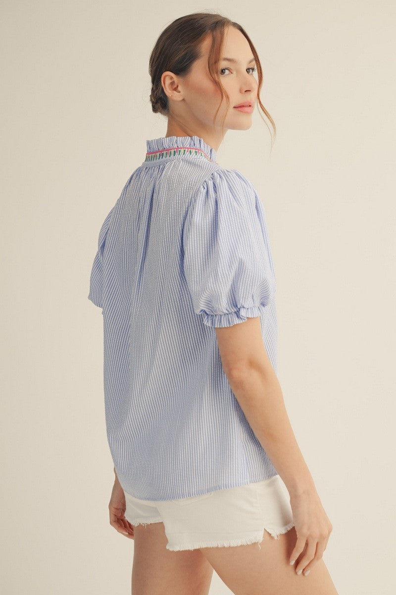 Short puff sleeve textured stripe top with embroidery accent and ruffled neckline in light neutral tone.