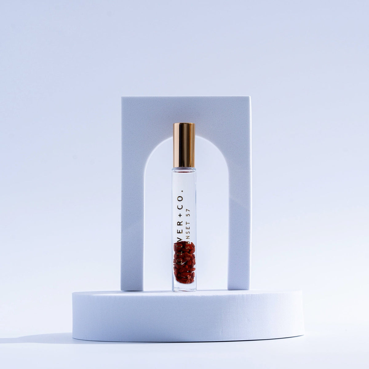 Bougie Stick Sunset 57 roll-on perfume with red crystals in a clear glass vial with a gold cap.