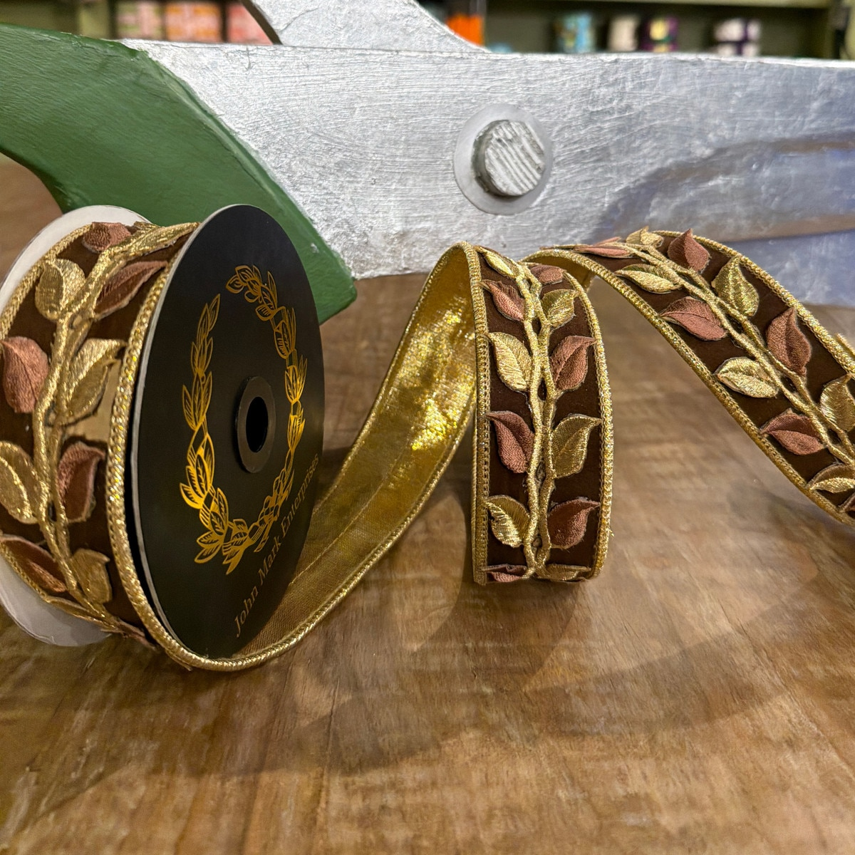 1.5 inch brown suede ribbon with metallic gold and copper laser-cut leaf trim on a spool.