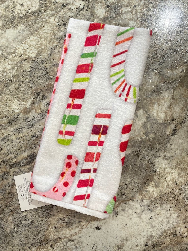 Holiday-themed tea towel with festive red and green patterns on a white kitchen cloth.