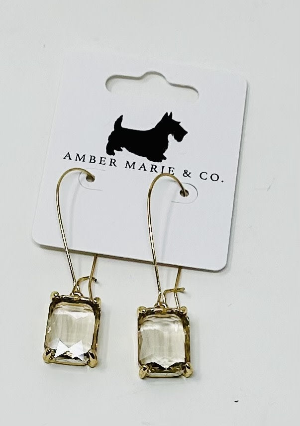 Gold-tone drop earrings featuring rectangular clear faceted stones on a white display card.