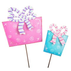 Two gift-shaped cupcake toppers with striped bows, one pink and one blue, on wooden sticks.