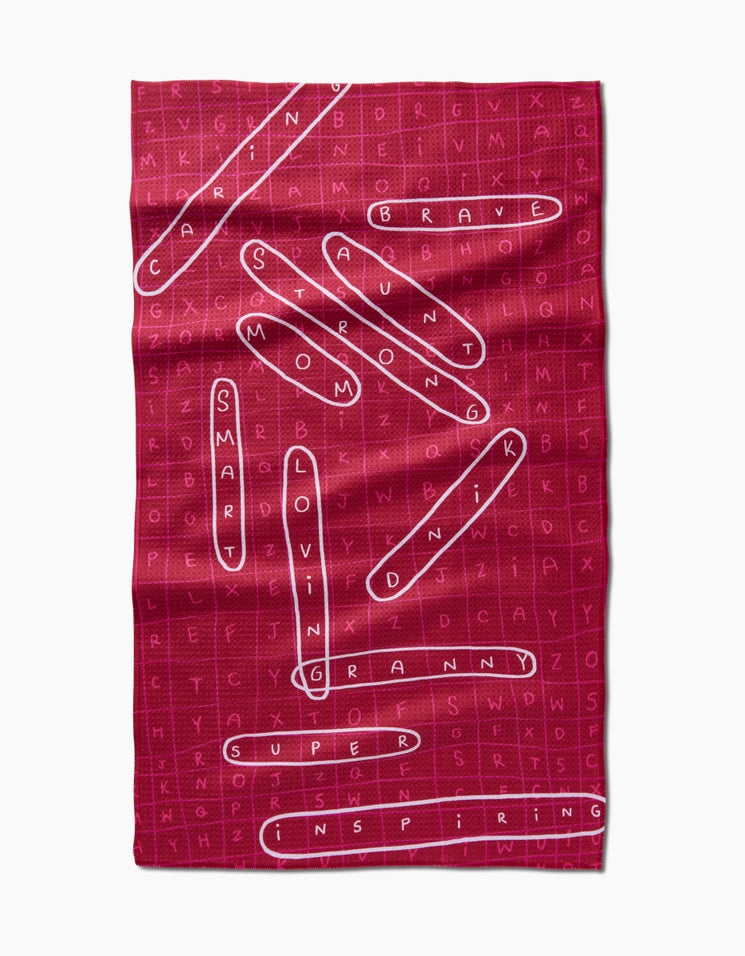 Pink waffle weave tea towel with a word search design highlighting words like BRAVE and SMART.