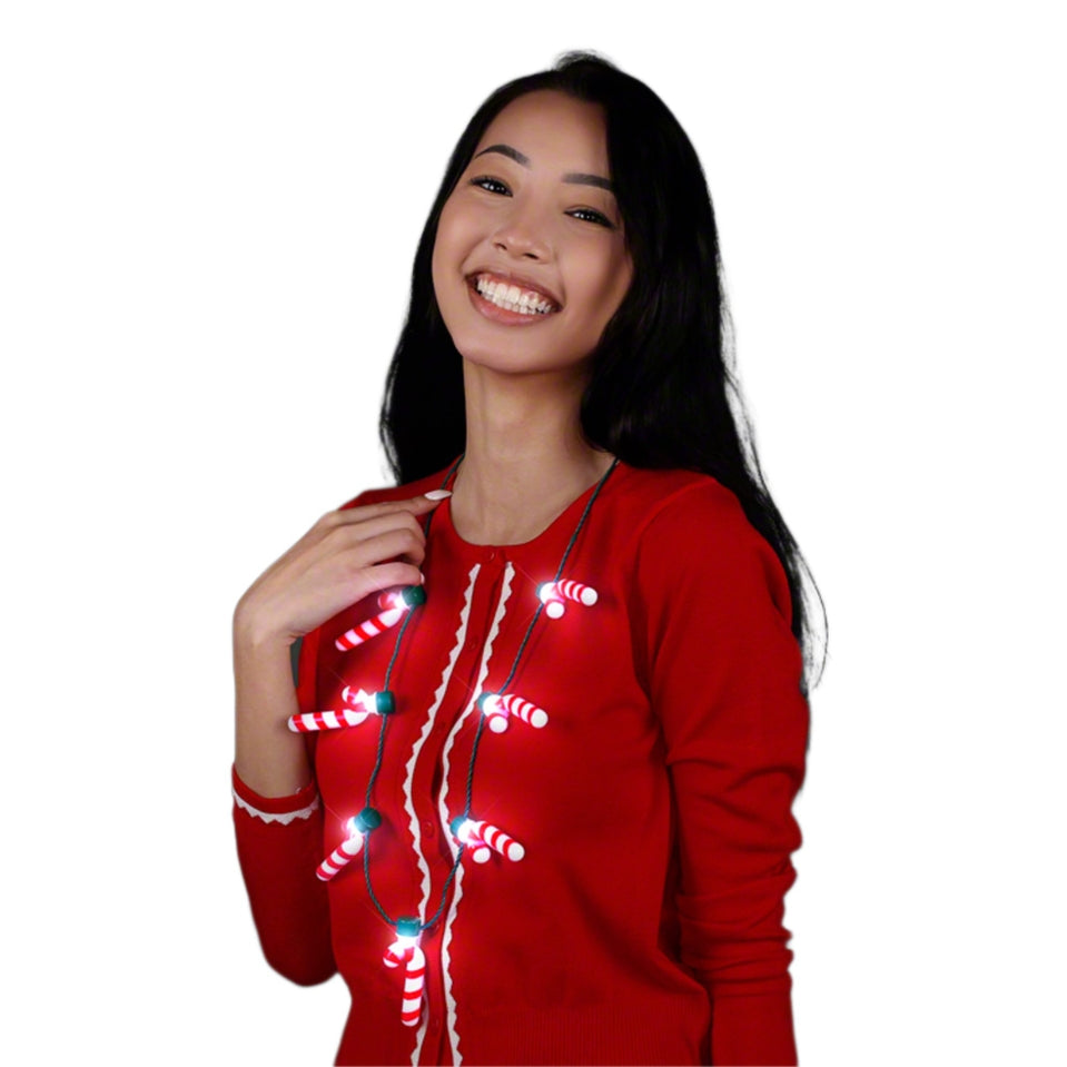 Woman wearing a Christmas necklace with seven light-up candy cane charms on a green cord.