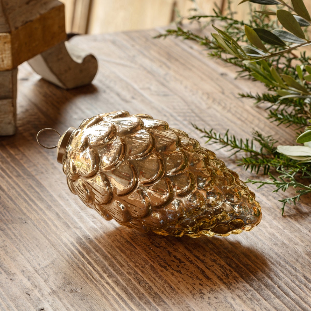 Pinecone Burnished Mercury Glass 7" Ornament on a rustic wooden surface.