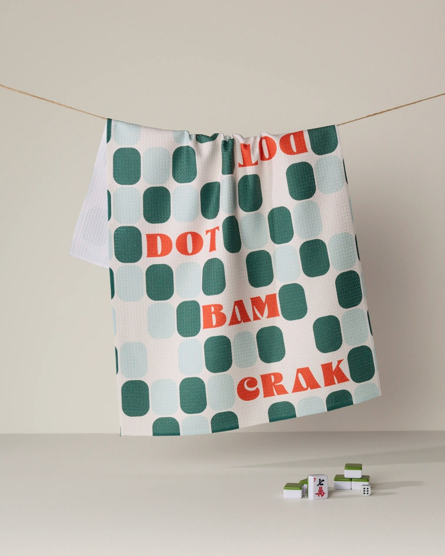 Everyday Tea Towel with green oval patterns and orange 'DOT', 'BAM', and 'CRAK' text on a clothesline.