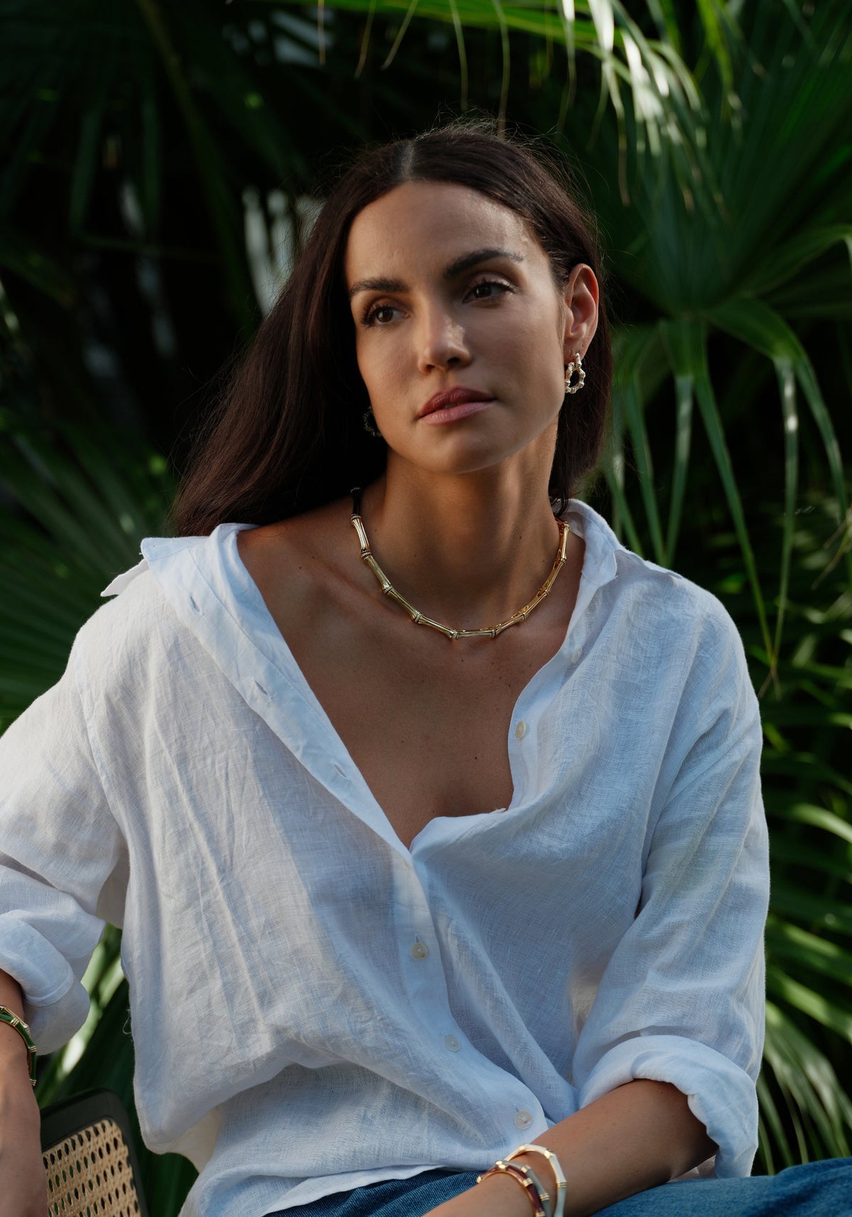 A woman wearing a gold-plated bamboo-style link necklace with crystal pavé accents.