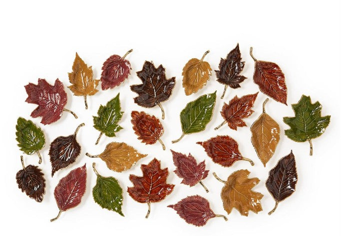 A collection of leaf-shaped trays in autumn colors with glossy enamel finishes and gold accents.
