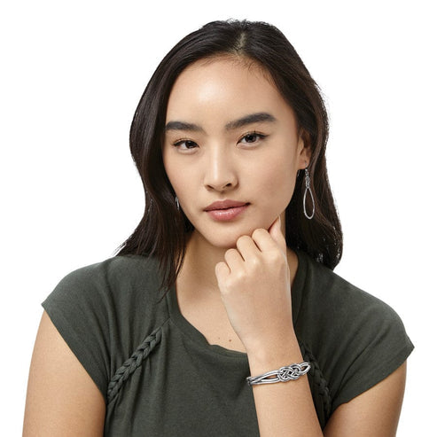 A woman wearing a silver-plated Interlok Hinged Bangle with a Celtic knot design.