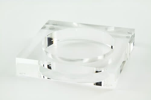 Clear square lucite wine bottle coaster with a circular recessed center.