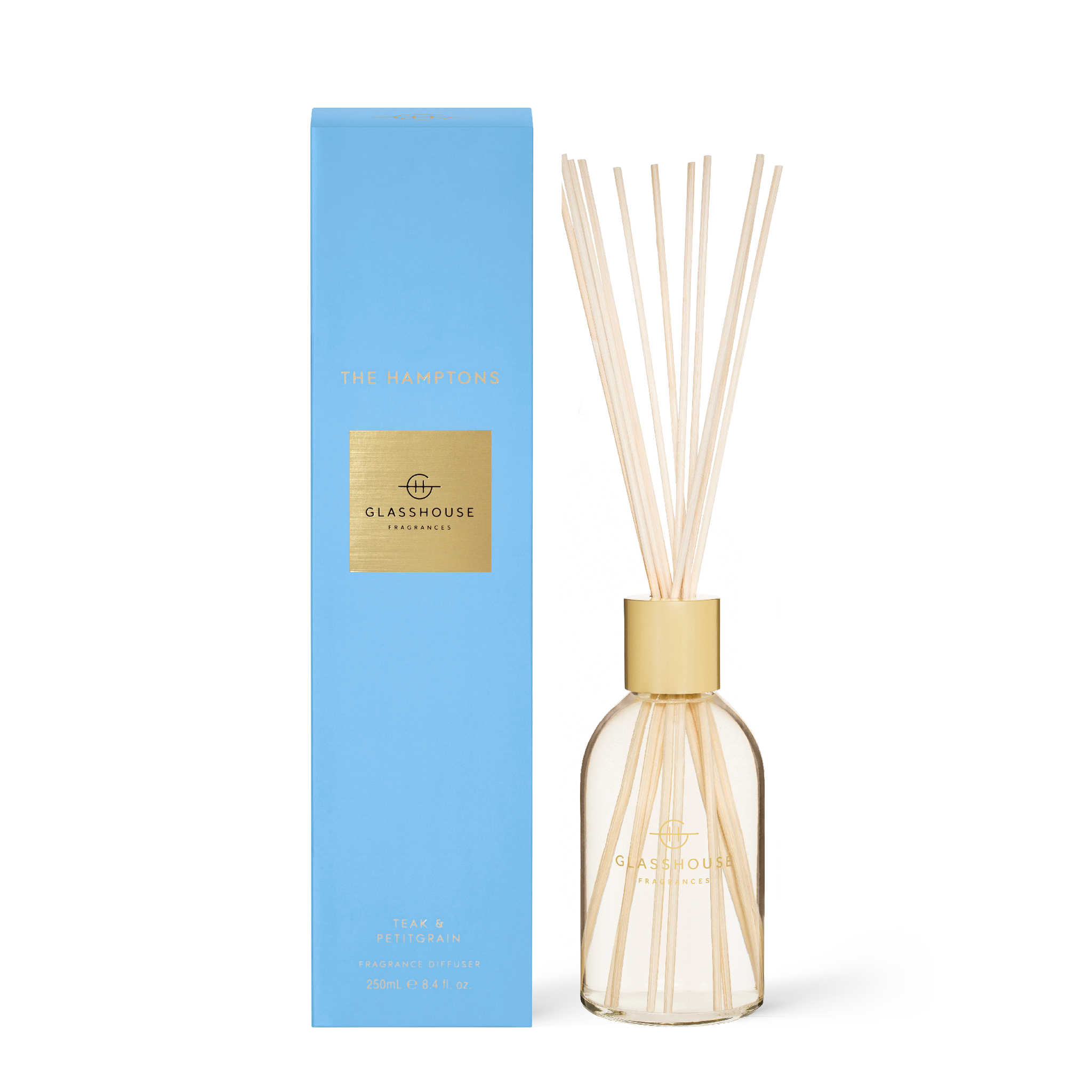 Glasshouse The Hamptons diffuser with amber liquid and reeds in a clear glass bottle.