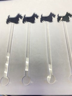 Four clear acrylic Scottie dog stir sticks with black dog silhouettes on top.