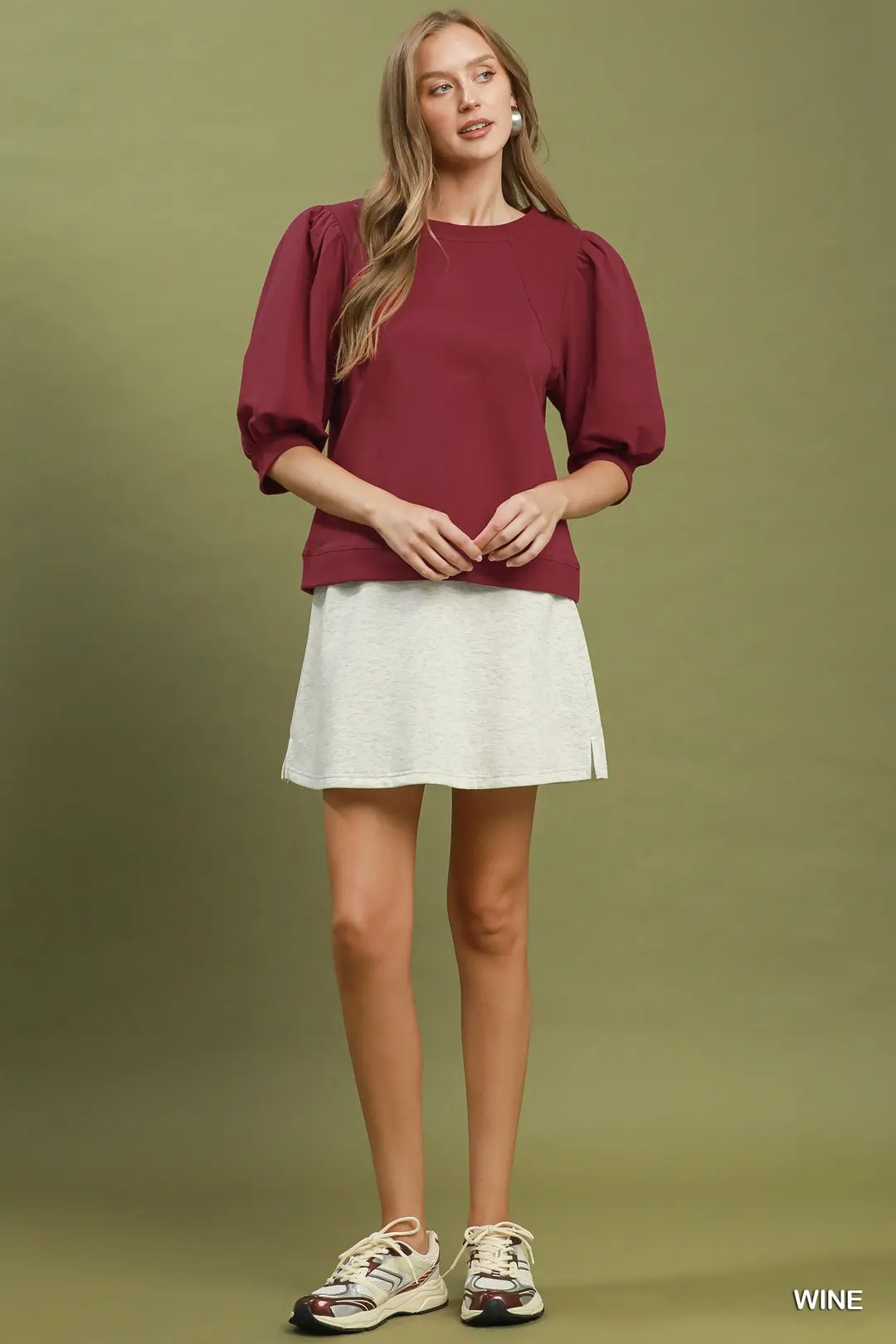 Woman wearing a wine-colored Joyce Puff Sleeve Pullover Sweatshirt with a light grey skirt.
