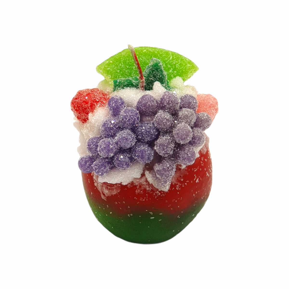 Candied apple candle shaped like a red and green apple topped with purple grapes and white frosting.