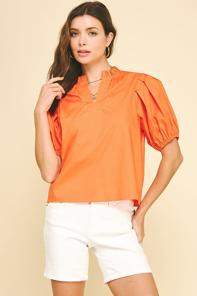 Orange cotton woven top with V-neckline, puff sleeves, and ruffle detailing at the neck.