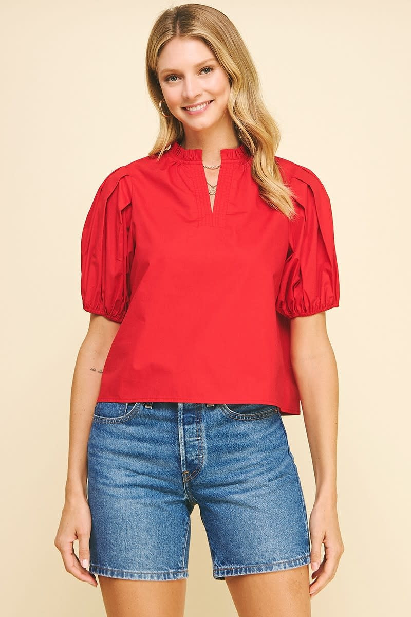 Fiery red woven V-neck top with puff sleeves and ruffle neckline.