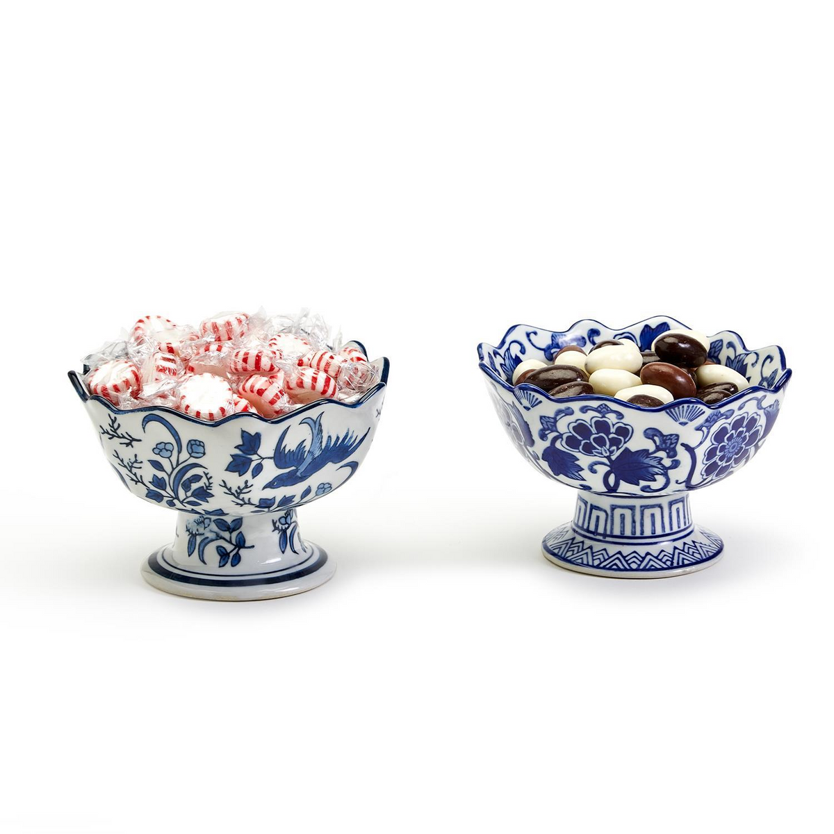 Two hand-painted blue and white porcelain footed bowls with scalloped edges filled with candy.
