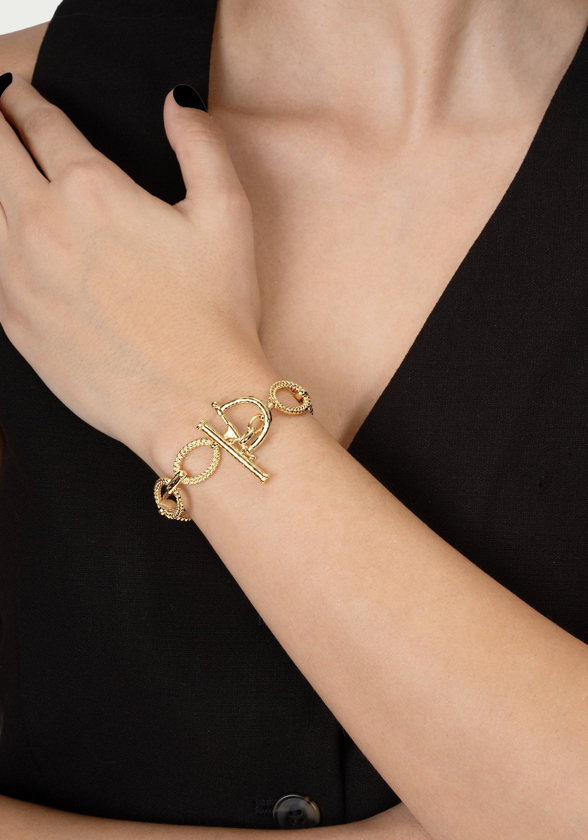 A person wearing the gold Cheval Chain Bracelet with a horse bit clasp on their wrist.