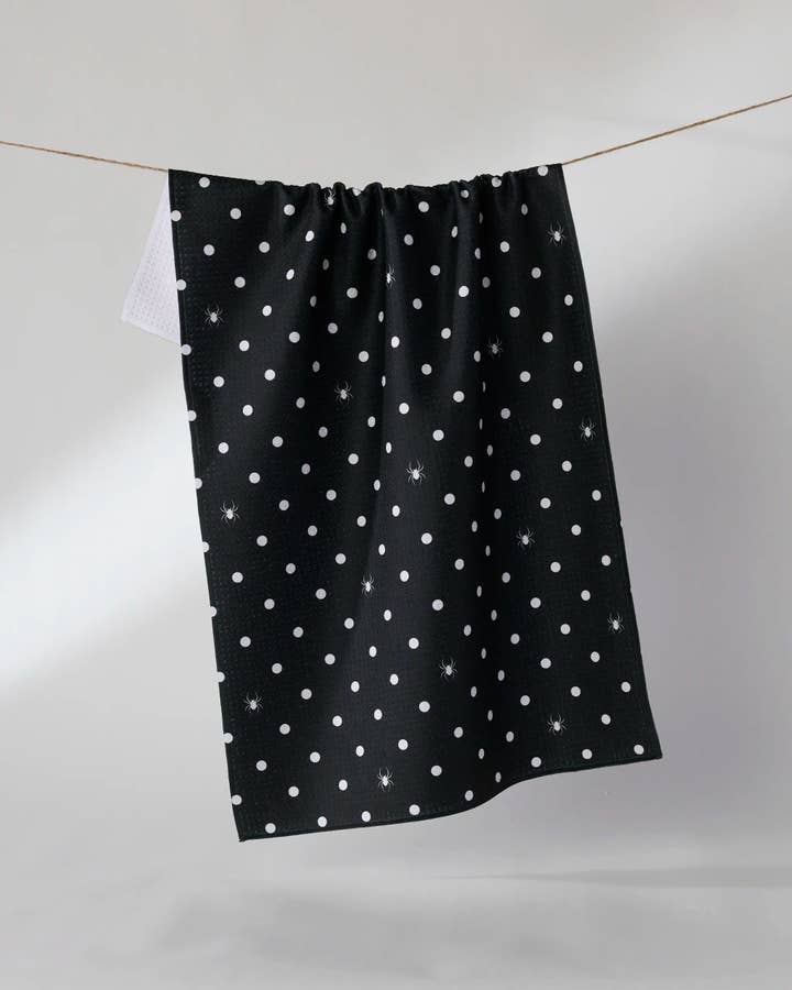 Black waffle weave Halloween tea towel with white polka dots and small spider graphics.