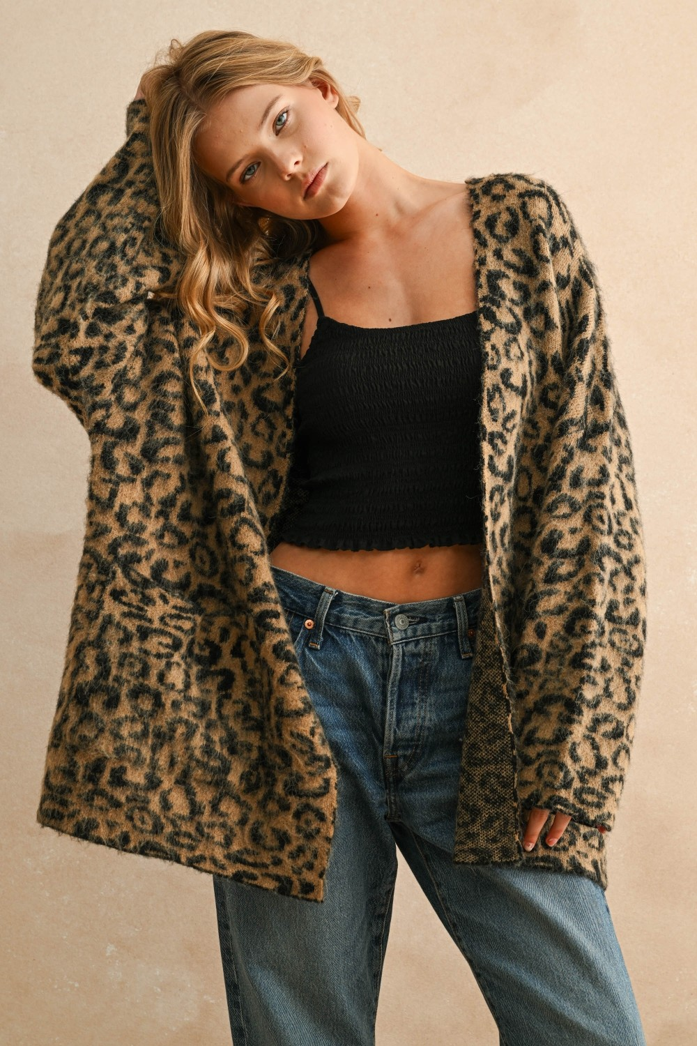 Woman wearing the Courtney Leopard Oversized Cardigan over a black crop top and blue jeans.