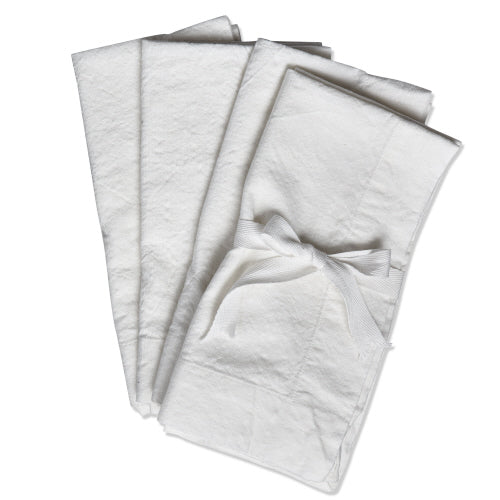 Set of four white slub fabric napkins folded and tied together with a matching white ribbon.