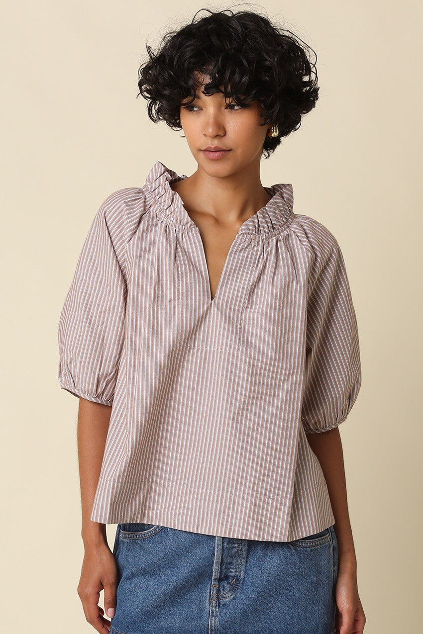 Woman wearing the Evan Stripe Puff Sleeve Blouse with a ruffle split neckline and blue denim.