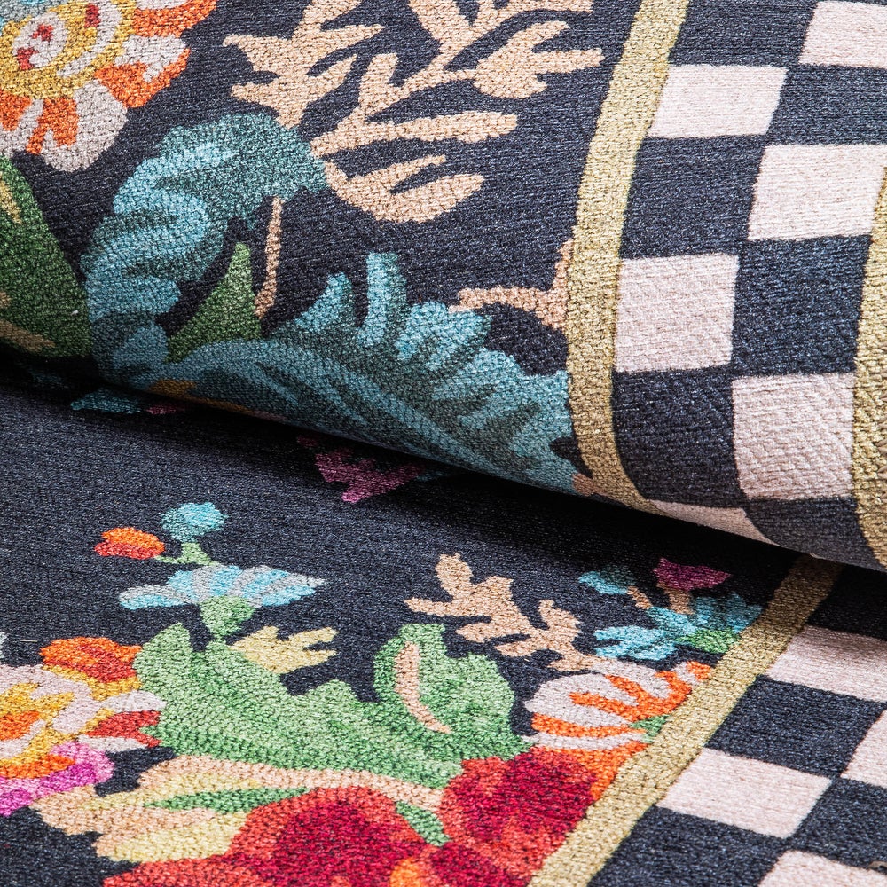 Close-up of a black rug featuring colorful floral patterns and a black and white checkered border.