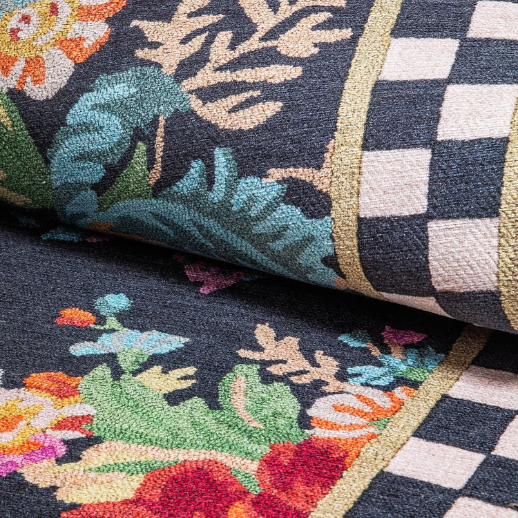 Close-up of a black rug featuring colorful floral patterns and a black and white checkered border.